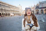Woman holding photo camera on Piazza San Marco and looking up