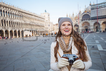 Woman holding photo camera on Piazza San Marco and looking up