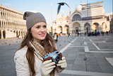 Young woman holding retro photo camera on Piazza San Marco