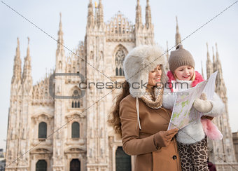 Mother and daughter looking on map while standing near Duomo