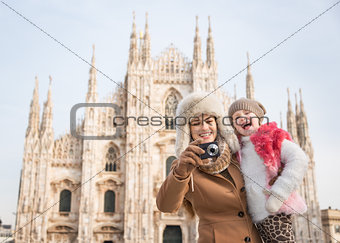 Happy mother and daughter taking photos in front of Duomo, Milan