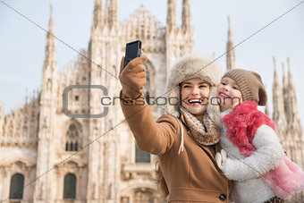 Happy mother and daughter taking selfie in front of Duomo, Milan