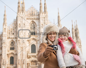 Smiling mother and daughter looking on photos near Duomo, Milan