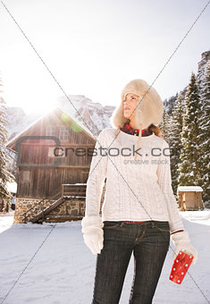 Woman in sweater looking up while standing near mountain house
