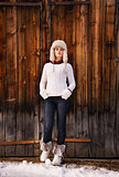 Full length portrait of woman standing near rustic wood wall