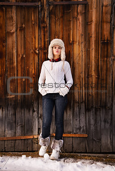 Full length portrait of woman standing near rustic wood wall