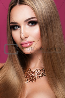 Beautiful young woman with long hair posing on pink shiny background.