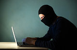 Hacker with a laptop in the mask