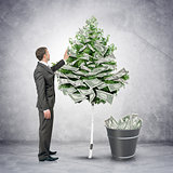 Businessman collecting money from tree