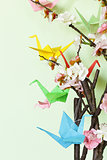 colorful paper origami birds on flowering branches of cherry (sakura)