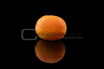a grapefruit with drops of water on black
