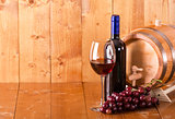 Glass of red wine bottle barrel and grapes