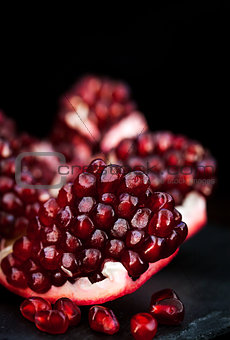 Fresh pomegranate and seeds on black