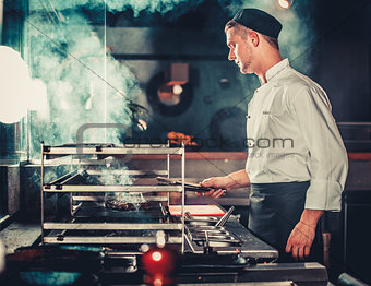 male cook preparing meal on grill