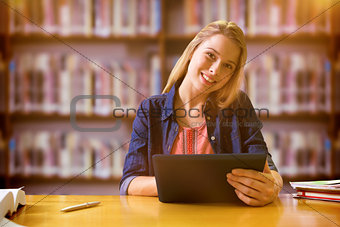 Composite image of student studying in the library with tablet