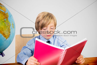 Composite image of cute pupil reading at desk