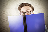 Composite image of geeky student reading a book