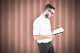 Composite image of geeky young man reading from black book