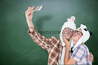 Composite image of geeky hipster couple taking selfie with smart phone