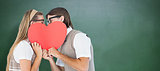Composite image of geeky hipsters kissing behind heart card