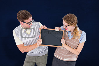 Composite image of geeky hipster couple holding little blackboard