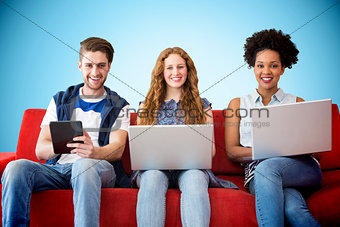 Composite image of young adults using electronic devices on couch