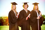 Composite image of three smiling students in graduate robe holding a diploma