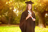 Composite image of a smiling woman with her degree as she looks at the camera