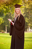 Composite image of blonde student in graduate robe holding a diploma