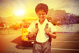 Composite image of cute pupil smiling at camera by the school bus
