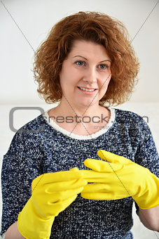 Woman takes off rubber gloves after cleaning