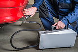 A diagnostic sensor is applied to the ehaust of a car by a mechanic, measuring the composition and substances in the exhaust fumes