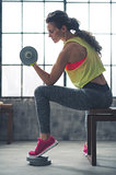 Fitness woman lifting dumbbell in loft gym