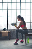 Athlete woman lifting dumbbell in loft gym