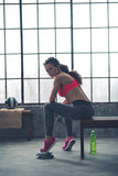 Fitness woman with dumbbell sitting in loft gym