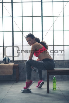 Fitness woman with dumbbell sitting in loft gym
