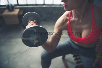 Closeup on fitness woman lifting dumbbell in loft gym