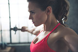 Fitness woman lifting dumbbell in loft gym
