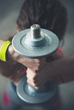Fitness woman holding dumbbell behind head. Close up