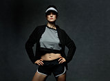 Young woman athlete posing against dark background