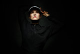 Fit woman in tennis visor looking up against black background