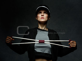Fit woman training with resistance band against dark background