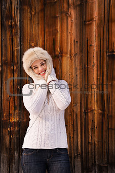 Happy woman in knitted sweater standing near rustic wood wall