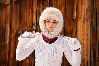 Young woman fooling around with furry hat near rustic wood wall