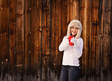 Happy woman in knitted sweater with cup near rustic wood wall