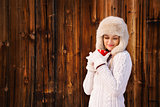 Relaxed and dreamy woman with red cup near rustic wood wall