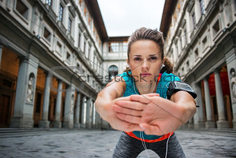 Sportswoman with headset is stretching next to Uffizi gallery