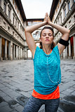 Fitness young woman with earphones doing yoga outdoors. Florence