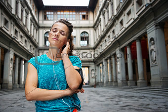 Portrait of relaxed young woman in sportswear listening mp3