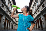 Sporty woman with headset is drinking water from the bottle